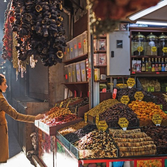 Une femme se tient devant un stand de fruits et légumes à Istanbul.