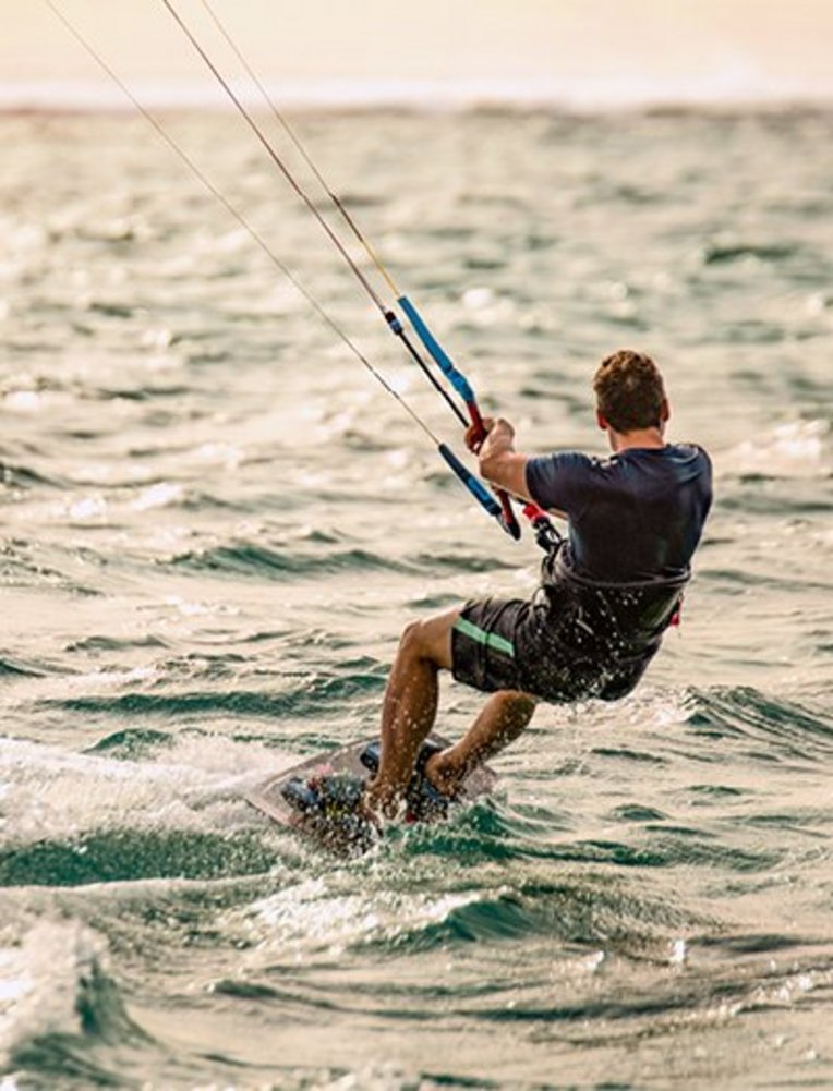 Ein Mann surft auf dem Wind in den Wellen des Ozeans vor der Küste von Mauritius.