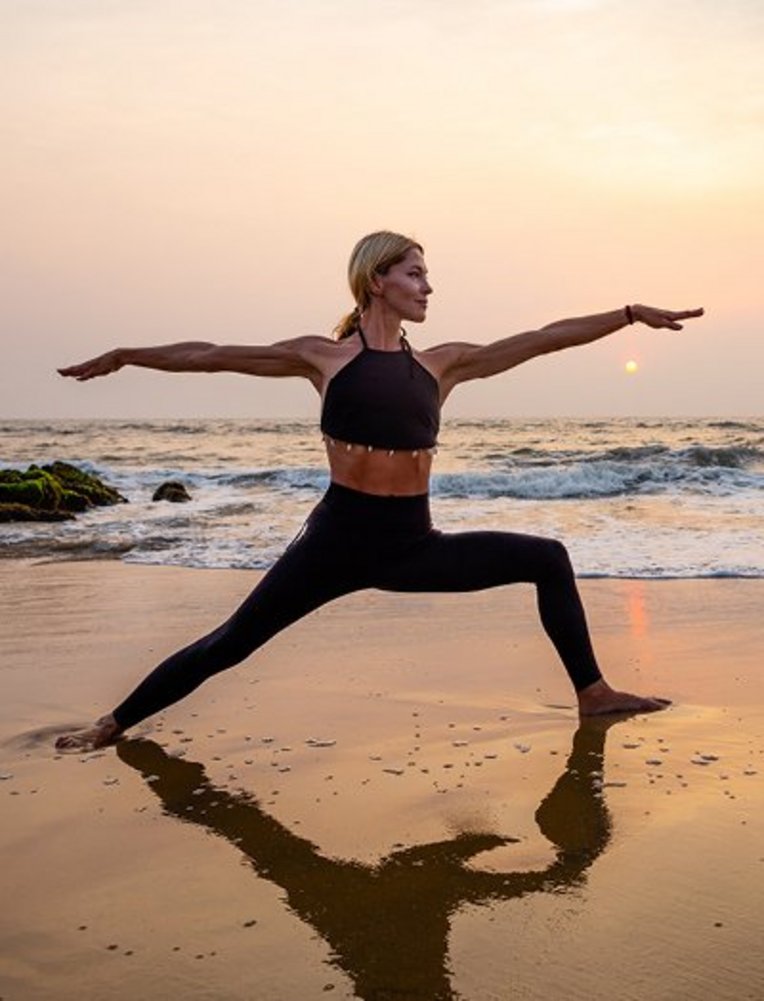 Frau praktiziert Yoga am Strand während des Sonnenuntergangs auf den Seychellen.