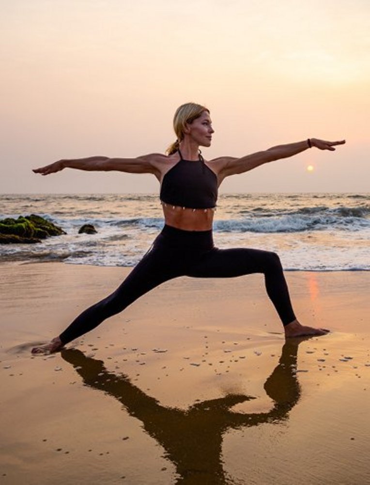 Frau praktiziert Yoga am Strand während des Sonnenuntergangs auf den Seychellen.