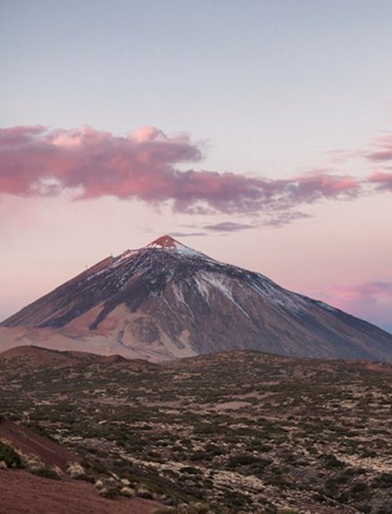 Teneriffa: Ein Berg unter einem rosa Himmel mit sanften Wolken.