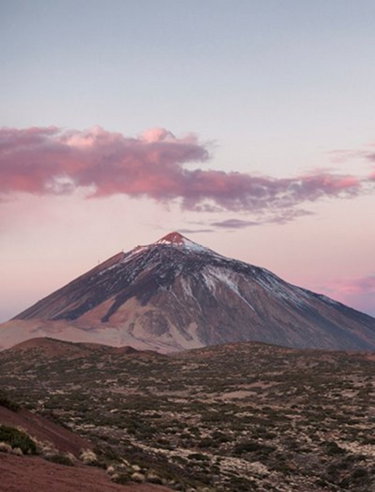 Teneriffa: Ein Berg unter einem rosa Himmel mit sanften Wolken.