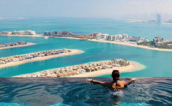 Eine Frau sitzt in einem Pool mit Blick auf den Ozean in Dubai.