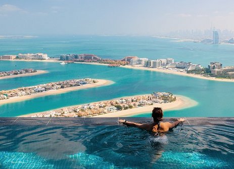Eine Frau sitzt in einem Pool mit Blick auf den Ozean in Dubai.