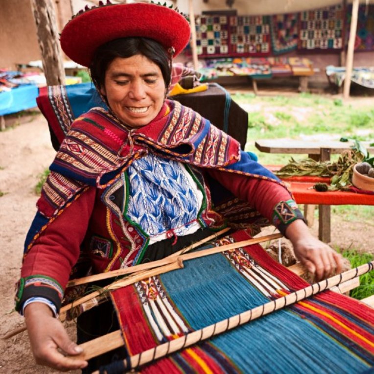 Woman in colourful traditional clothing weaving textiles