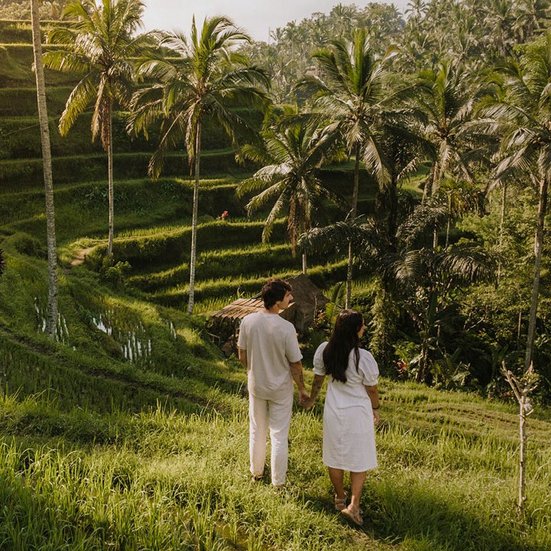 Ein Paar spaziert durch die Reisfelder in Ubud, Bali, umgeben von üppigem Grün und malerischer Landschaft.