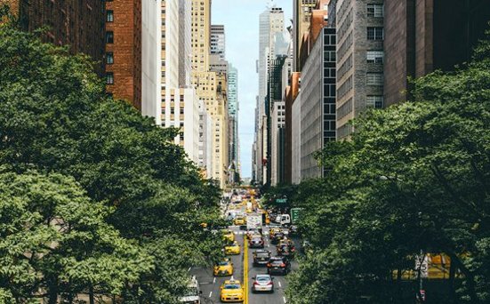 Eine Stadtstrasse in NYC mit einem gelben Taxi, das auf der Strasse fährt.