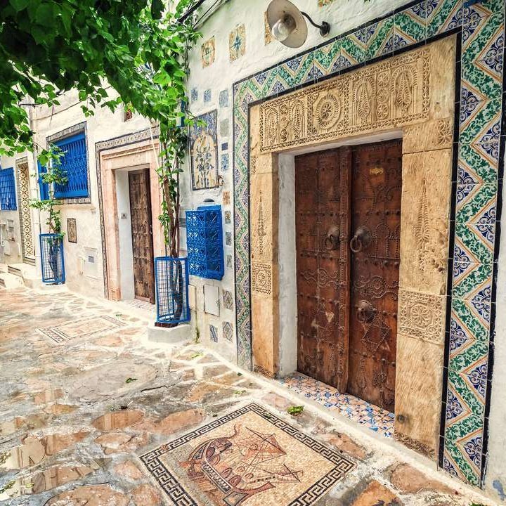 Enge Strasse in Tunisien mit blauen und weissen Gebäuden, die eine charmante Atmosphäre schaffen.