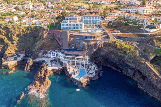 Luftbild des Hotels mit weissem Gebäude in eine Klippe gebaut mit Zugang zum blauem Meer