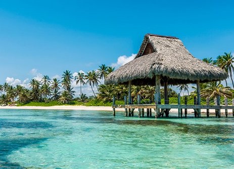 Ein Strand in Punta Cana mit einer Strohhütte und Palmen im Hintergrund.