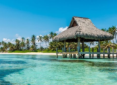 Ein Strand in Punta Cana mit einer Strohhütte und Palmen im Hintergrund.