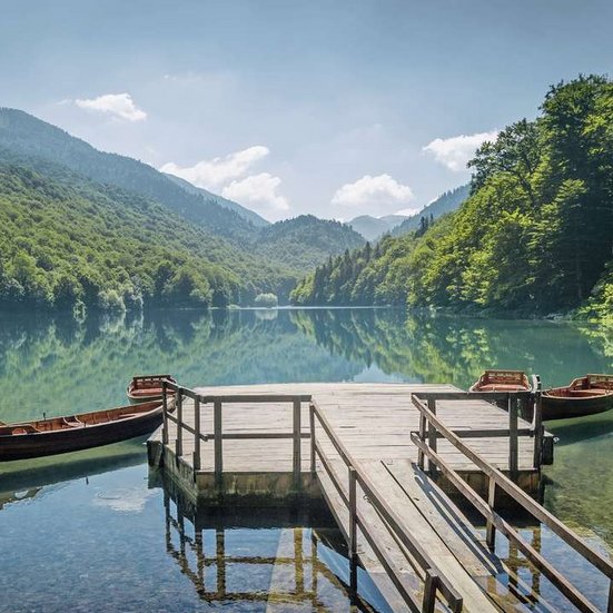 Zwei Boote liegen am Steg eines Sees in Montenegro, umgeben von majestätischen Bergen.