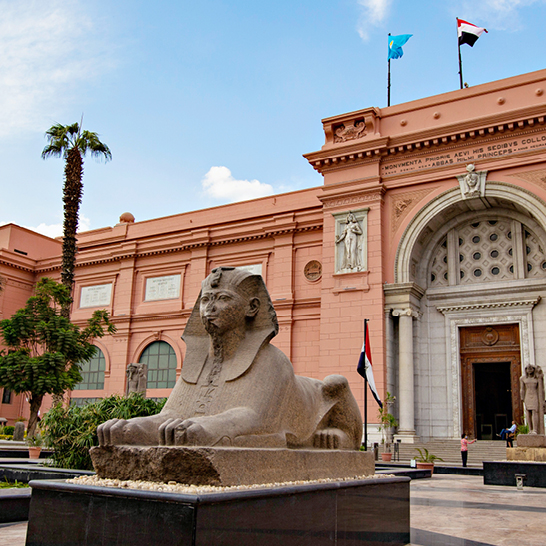 Un grand bâtiment avec une statue de sphinx imposante devant, représentant le musée égyptien.