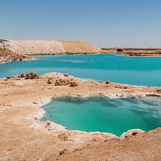 Une grande étendue d'eau avec une petite piscine au centre, représentant l'Oasis de Siwa.