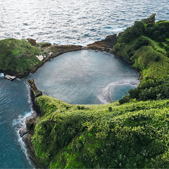 Küstenbucht auf São Miguel, umgeben von grünen Klippen.