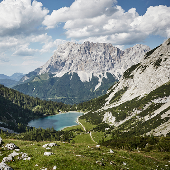 Klarer Bergsee unterhalb der Zugspitze, umgeben von steilen Felswänden und dichtem Alpenwald.