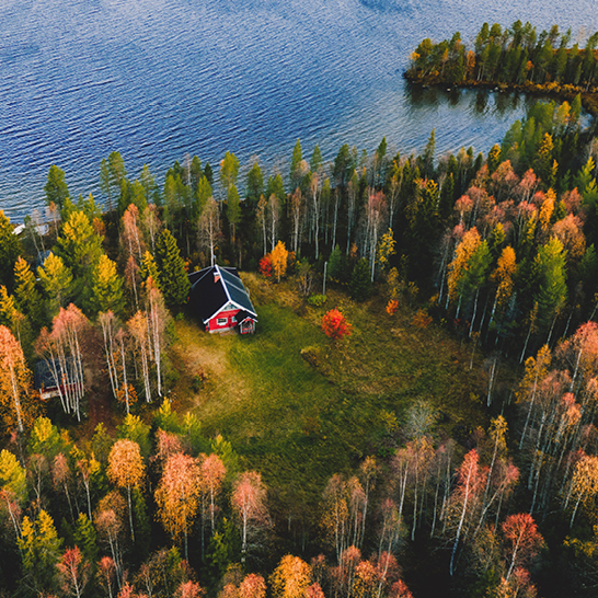 Vue aérienne d'une maison rouge entourée d'arbres en Finlande.