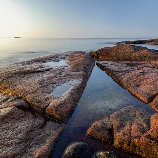 Rochers et eau au coucher du soleil sur la côte des Îles Åland.