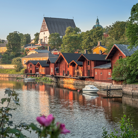 Une rivière avec quelques maisons rouges et une église à Porvoo.