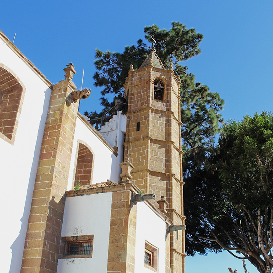 Les foules profitent de la plage ensoleillée de Gran Canaria, tandis que la majestueuse basilique de Teror domine à proximité.