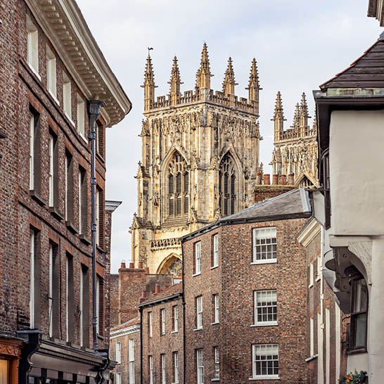 York Minster zwischen historischen Backsteingassen, mit gotischen Türmen im Hintergrund.