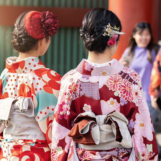 Un groupe de femmes en vêtements traditionnels japonais, souriantes, posant ensemble dans un cadre culturel japonais.