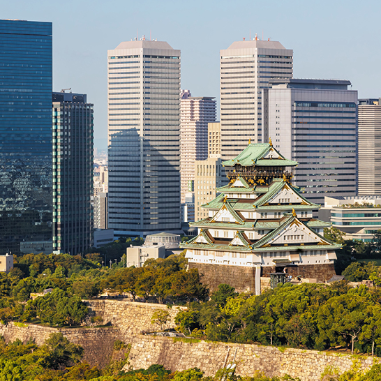 Une vue de la skyline d'une ville japonaise avec un grand bâtiment au premier plan.