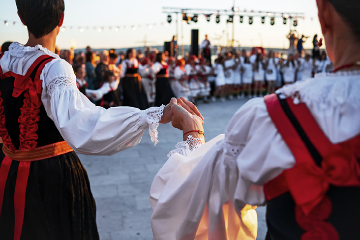 Traditioneller kroatischer Volkstanz mit Tänzerinnen und Tänzern in regionalen Trachten während einer festlichen Aufführung.