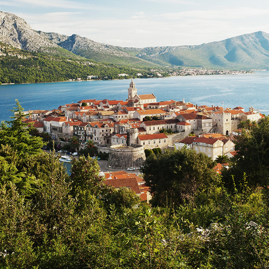 Historische Altstadt der Insel Korčula mit steinernen Häusern, terrakottafarbenen Dächern und Blick auf die Bucht.
