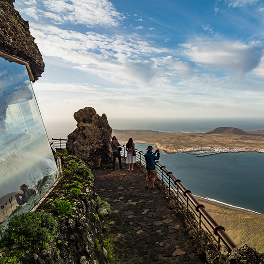Des personnes se tiennent au bord d'une falaise et admirent la vue sur l'océan au Mirador del Río, à Lanzarote.