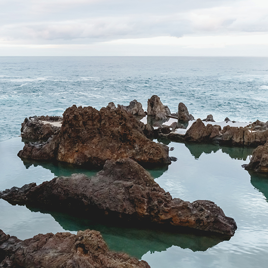 Rochers dans l'océan, avec des vagues et un ciel bleu en arrière-plan.