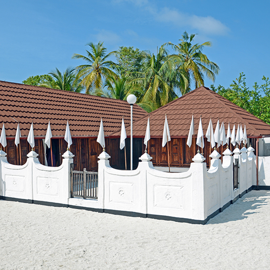 Weißes Gebäude, geschmückt mit weißen und braunen Flaggen, vor blauem Himmel.