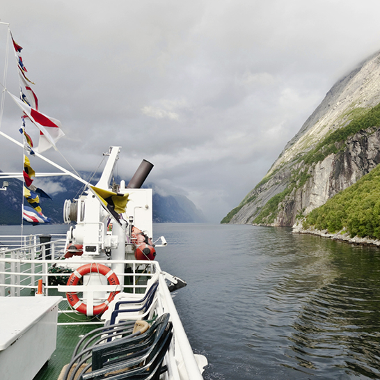 Ein Boot auf dem Wasser mit majestätischen Fjorden und Bergen im Hintergrund in Norwegen.