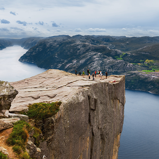 Eine Gruppe von Menschen steht auf einer Klippe und blickt auf das Wasser in Stavanger.