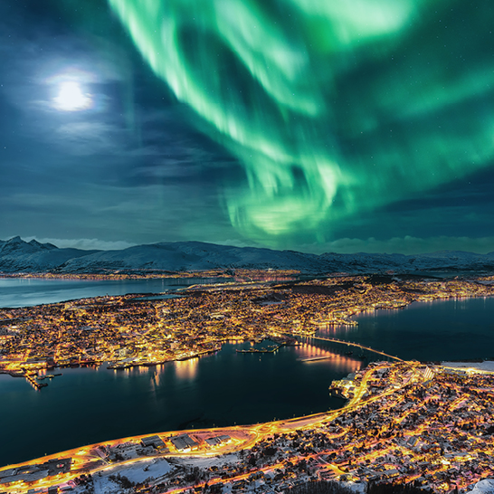 Aurora Borealis über der Stadt Tromsø in Fjordaland, Norwegen, mit leuchtenden Farben am Nachthimmel.