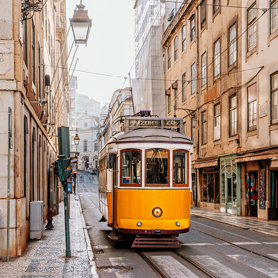 Un trolley car jaune et blanc sur une rue étroite.