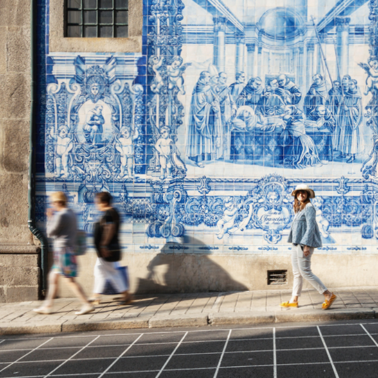 Une femme se promène dans la rue, vêtue d'une robe d'été et des lunettes de soleil.