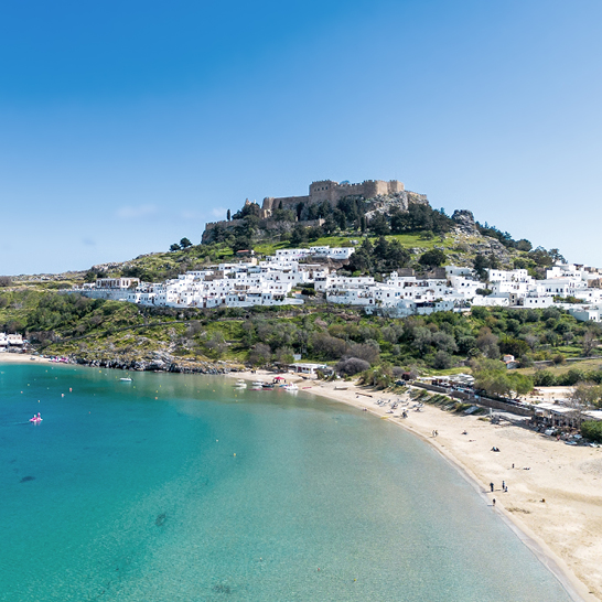 Vue sur l’Acropole de Lindos à Rhodes, dominant le village blanc et la baie turquoise.