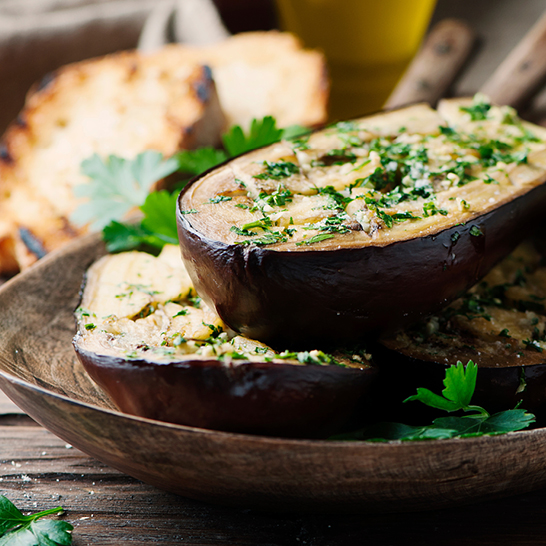 Ein Teller mit Auberginen, frischem Brot und Petersilie, typisch für die sardische Küche.