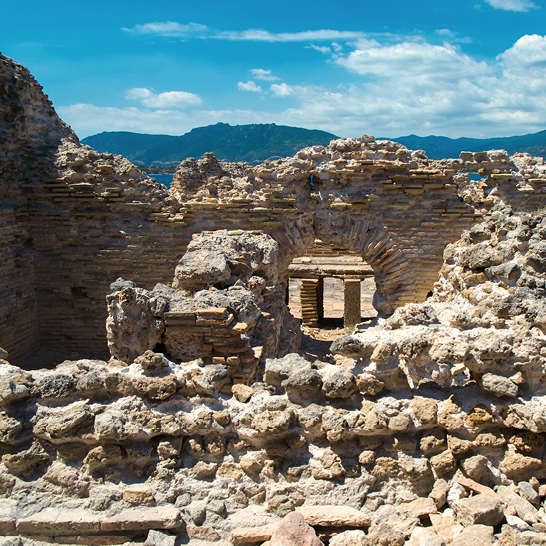 Ruinen eines Gebäudes in der Wüste von Sardinien, umgeben von sandigen Dünen und kargem Gelände.