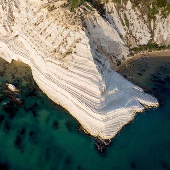 Blick auf die Scala dei Turchi mit ihren weissen, terrassenfoermigen Klippen, die in das tuerkisfarbene Meer abfallen.