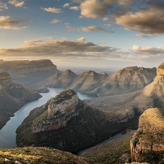 Blyde River Canyon mit steilen Felswänden und Fluss im Tal unter weichem Sonnenlicht.