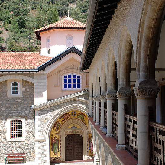 Innenhof des Kykkos-Klosters mit Arkadengang, verzierten Fassaden und terrakottafarbenen Dächern in den Bergen Zyperns.